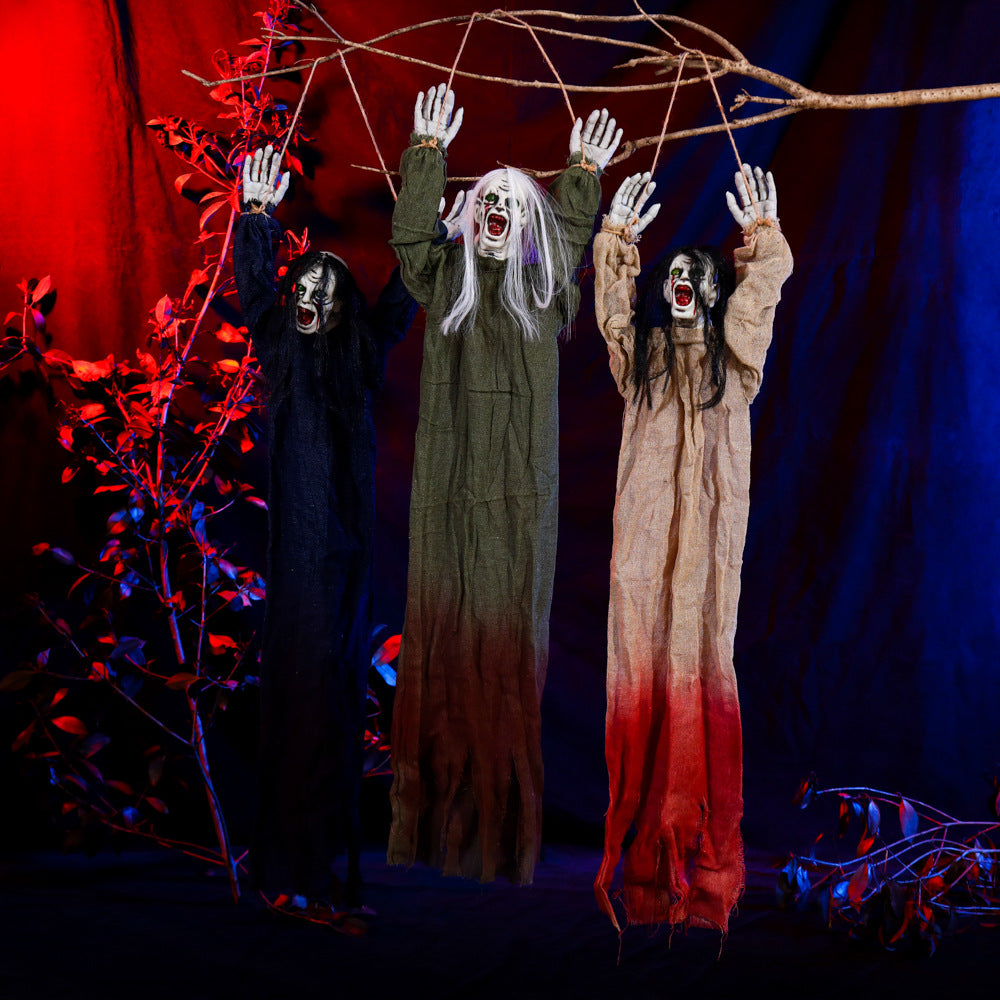 Trois fantômes Halloween aux bras levés suspendus à une branche, en vêtements bleu, vert et beige.
