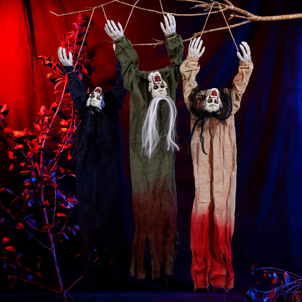 Trois fantômes Halloween en tissu bleu, vert et beige suspendus à une branche.

